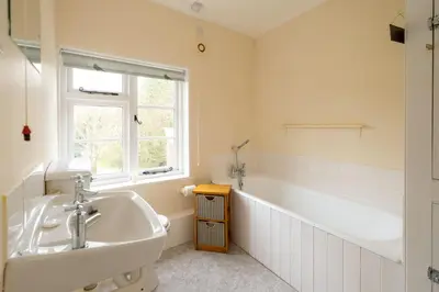 a bathroom with a sink and a tub and a window at Mere Cottage - Aldeburgh Coastal Cottages in Thorpeness