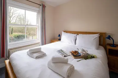 a white bed with towels and a tray of food on it at Mere Cottage - Aldeburgh Coastal Cottages in Thorpeness