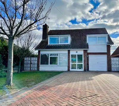 a house with a brick driveway and a tree at Island House in West Mersea