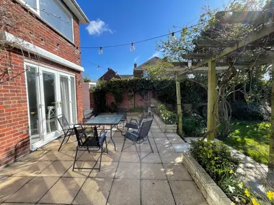 a patio with a table and chairs next to a brick building at Island House in West Mersea
