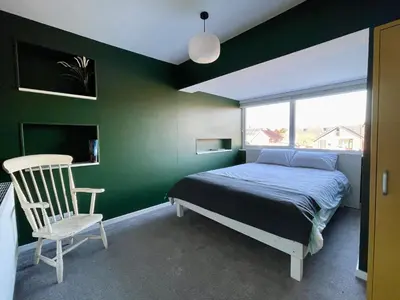 a bedroom with green walls and a bed and a chair at Island House in West Mersea