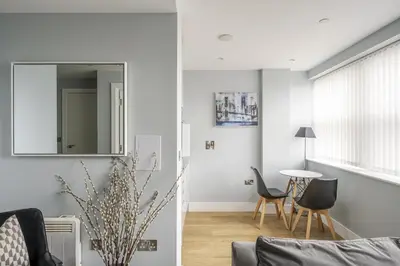 a living room with white walls and a mirror at Luxury Apartment in Chelmsford Bond Street with Sky TV, Movies & Netflix in Chelmsford