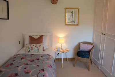 a bedroom with a bed and a table and a chair at May Barn, Ixworth in Ixworth