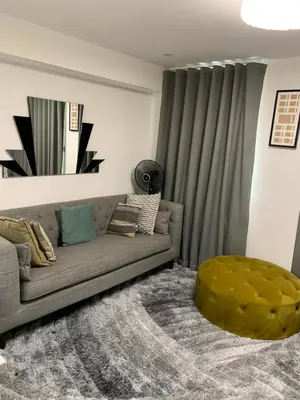 a living room with a couch and a green ottoman at A BYK luxury modern home that sleeps 2 - 8 people in Horndon on the Hill