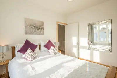 a bedroom with a white bed with purple pillows at Beautiful and Spacious Cambridge Home with Free Parking & Garden! in Cambridge