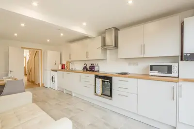 a white kitchen with white cabinets and a microwave at Beautiful and Spacious Cambridge Home with Free Parking & Garden! in Cambridge