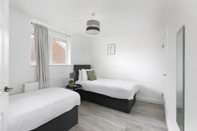 two beds in a room with white walls and a window at Skyvillion - STEVENAGE SPACIOUS & COZY 3Bed House with Parking, Wifi, Garden in Aston End