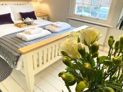 a bedroom with a bed and a plant in the foreground at 6 Coastguard Cottages, Aldeburgh in Aldeburgh