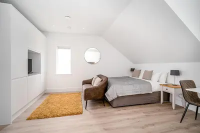 a white bedroom with a bed and a chair at Citystay Living - Finch House in Cambridge