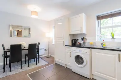 a kitchen with a washing machine and a table with chairs at Velvet 2-bedroom apartment, Brewery Road, Hoddesdon in Hoddesdon