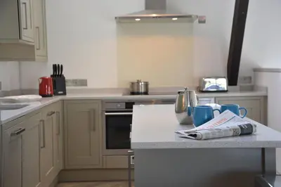 a kitchen with white cabinets and a counter top at Badminton, Thorpeness in Thorpeness