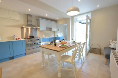 a kitchen with blue cabinets and a table and chairs at Somewhere Only We Know, Aldeburgh in Aldeburgh