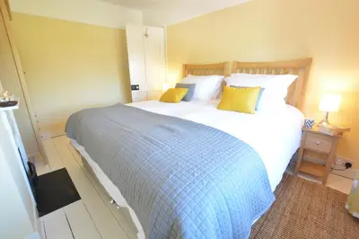 a bedroom with a large white bed with yellow pillows at Somewhere Only We Know, Aldeburgh in Aldeburgh