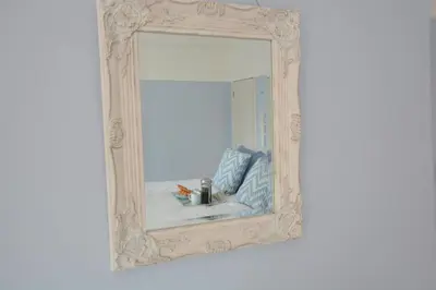 a mirror with a white frame on a white wall at Somewhere Only We Know, Aldeburgh in Aldeburgh