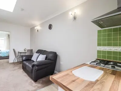 a living room with a leather couch and a stove at 493 Little Wakering Road in Southend-on-Sea