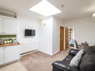 a living room with a leather couch and a kitchen at 493 Little Wakering Road in Southend-on-Sea