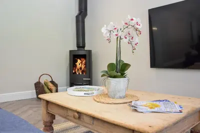 a wooden table with a vase of flowers and a fireplace at The Piglets in Woodbridge