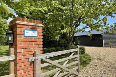 a brick fence and a gate with a sign on it at The Piglets in Woodbridge