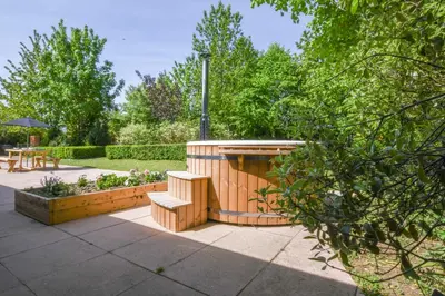 a garden with a bench and a table and trees at The Piglets in Woodbridge