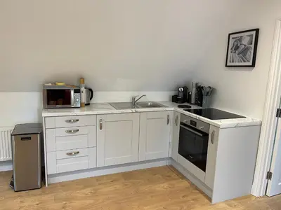 a kitchen with white cabinets and a sink and a microwave at Debussys Guest House in Saffron Walden