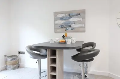 a dining room table with two black stools at Corner Cottage, Thorpeness in Thorpeness