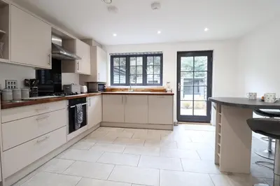 a kitchen with white cabinets and a black counter at Corner Cottage, Thorpeness in Thorpeness