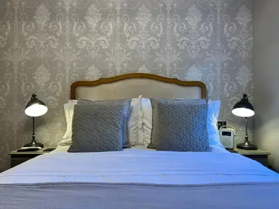 a bedroom with a bed with blue sheets and two lamps at Glanthams Lodge Guestroom in Shenfield