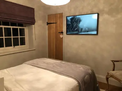 a bedroom with a tv hanging on the wall at Glanthams Lodge Guestroom in Shenfield