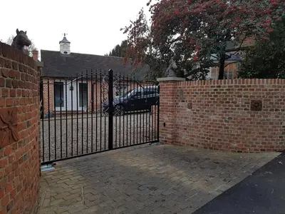 a brick fence with a gate in front of a house at Glanthams Lodge Guestroom in Shenfield