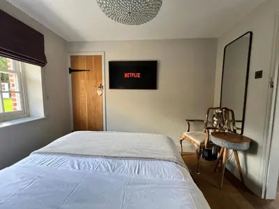 a bedroom with a bed and a chair and a window at Glanthams Lodge Guestroom in Shenfield