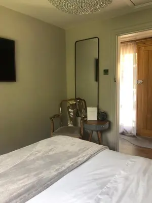 a bedroom with a bed and two chairs and a mirror at Glanthams Lodge Guestroom in Shenfield