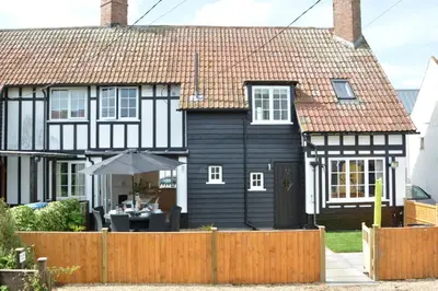 a black and white house with a wooden fence at 4 The Dunes, Thorpeness in Thorpeness