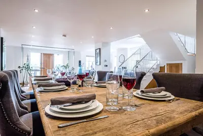 a wooden table with wine glasses and plates on it at Guild House, Aldeburgh in Aldeburgh