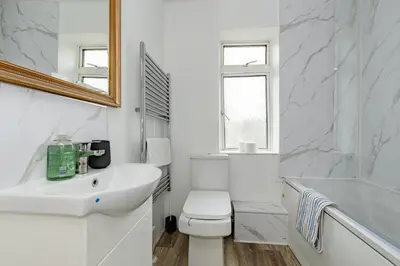a white bathroom with a toilet and a sink at The Comfy Contractors Resort, Free Private Parking & Wifi, 7 beds in Colchester