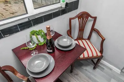 a wooden table with a bottle of wine and a chair at The Comfy Contractors Resort, Free Private Parking & Wifi, 7 beds in Colchester