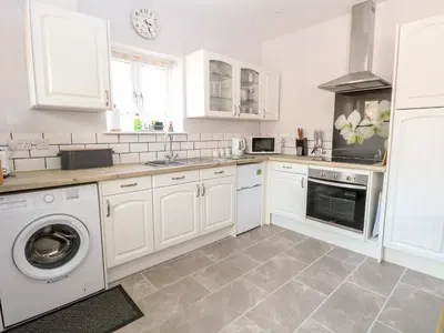 a kitchen with white cabinets and a washing machine at Jimmys Place in Diss