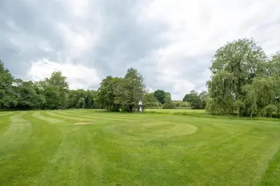 a golf course with a green field and trees at The Cart Lodge - Aldeburgh Coastal Cottages in Wickham Market