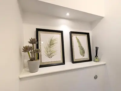 two framed prints of plants on a shelf in a bathroom at CENTRAL CAMBRIDGE, CHARMING 3-Bed HOUSE WITH FREE PARKING! in Cambridge