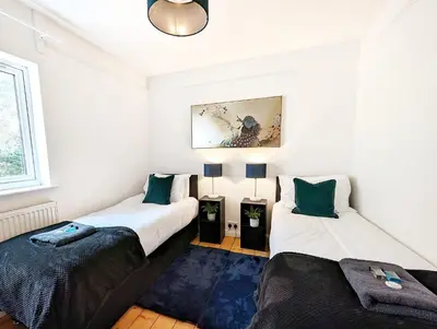 two beds in a room with white walls at CENTRAL CAMBRIDGE, CHARMING 3-Bed HOUSE WITH FREE PARKING! in Cambridge