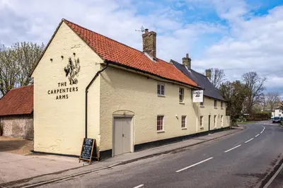 a white building on the side of a street at The Carpenters Arms in Great Wilbraham