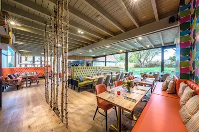 a restaurant with tables and chairs and windows at The Carpenters Arms in Great Wilbraham
