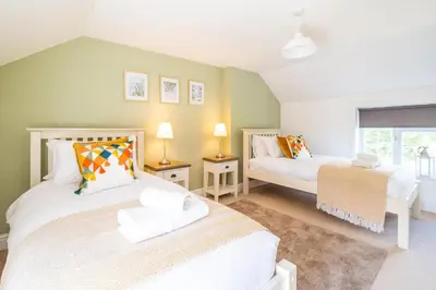 a bedroom with two beds and a window at Laurel Cottage - Aldeburgh Coastal Cottages in Blyford