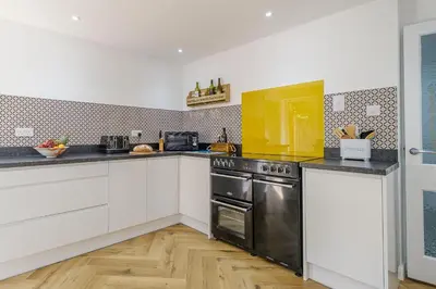 a kitchen with white cabinets and a stainless steel oven at Skippers Cottage - Aldeburgh Coastal Cottages in Aldeburgh