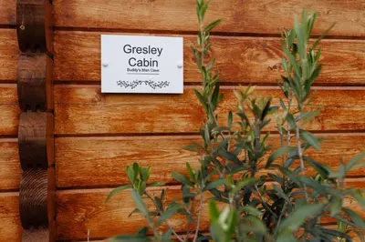 a sign on a wooden wall with a plant at Spacious Cabin EVCharger and free Parking near Cambridge in Cambridge