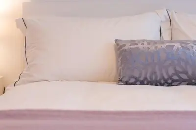 a bed with white sheets and pillows and a pillow at New stylish 4 bed house moments from Clacton beach in Clacton-on-Sea