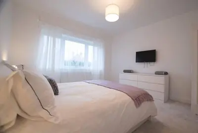 a white bedroom with a bed and a television at New stylish 4 bed house moments from Clacton beach in Clacton-on-Sea