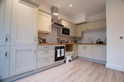 a kitchen with white cabinets and a wooden floor at New stylish 4 bed house moments from Clacton beach in Clacton-on-Sea
