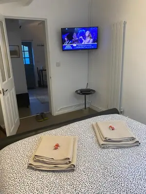 two towels on a bed with a television on the wall at Self-contained, Framlingham Snug, Private Parking, no cooking facilities in Framlingham