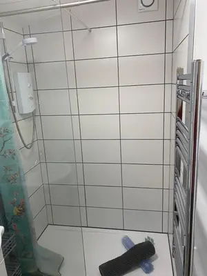 a shower in a bathroom with a black and white tile wall at Self-contained, Framlingham Snug, Private Parking, no cooking facilities in Framlingham