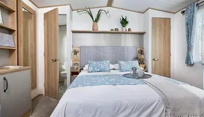 a bedroom with a large bed with blue pillows at Mersea Villa in West Mersea